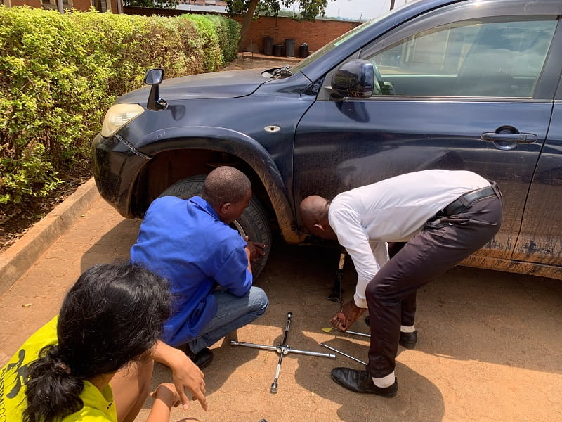 Locals assist changing a tire for Ryan Wilkins in Malawi