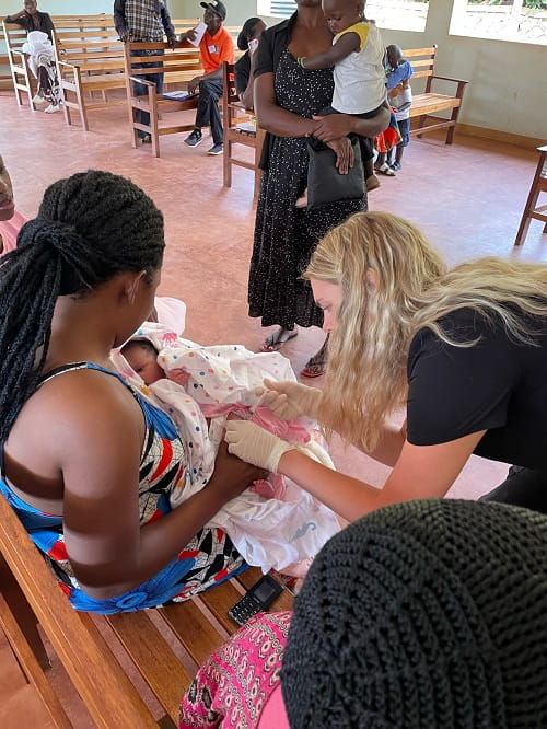 Sierra Simmons, working on a project in Uganda, cares for a local child.