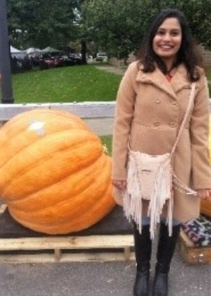 Photo of Amanda standing in front of a giant pumpkin.