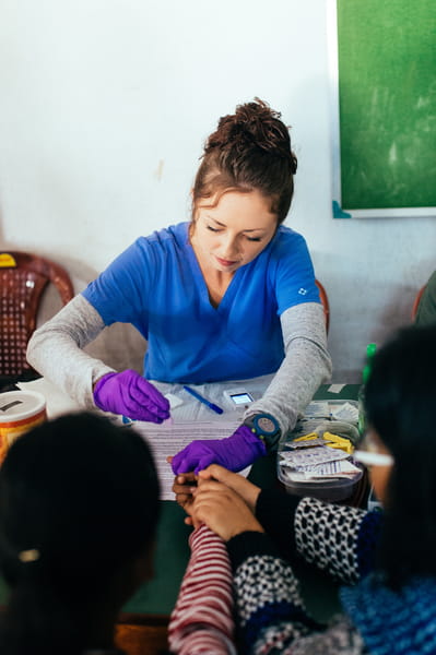 Nursing student takes a blood sample from a patient in India.