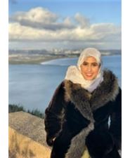 Photo of Shahad standing in front of a coastline.