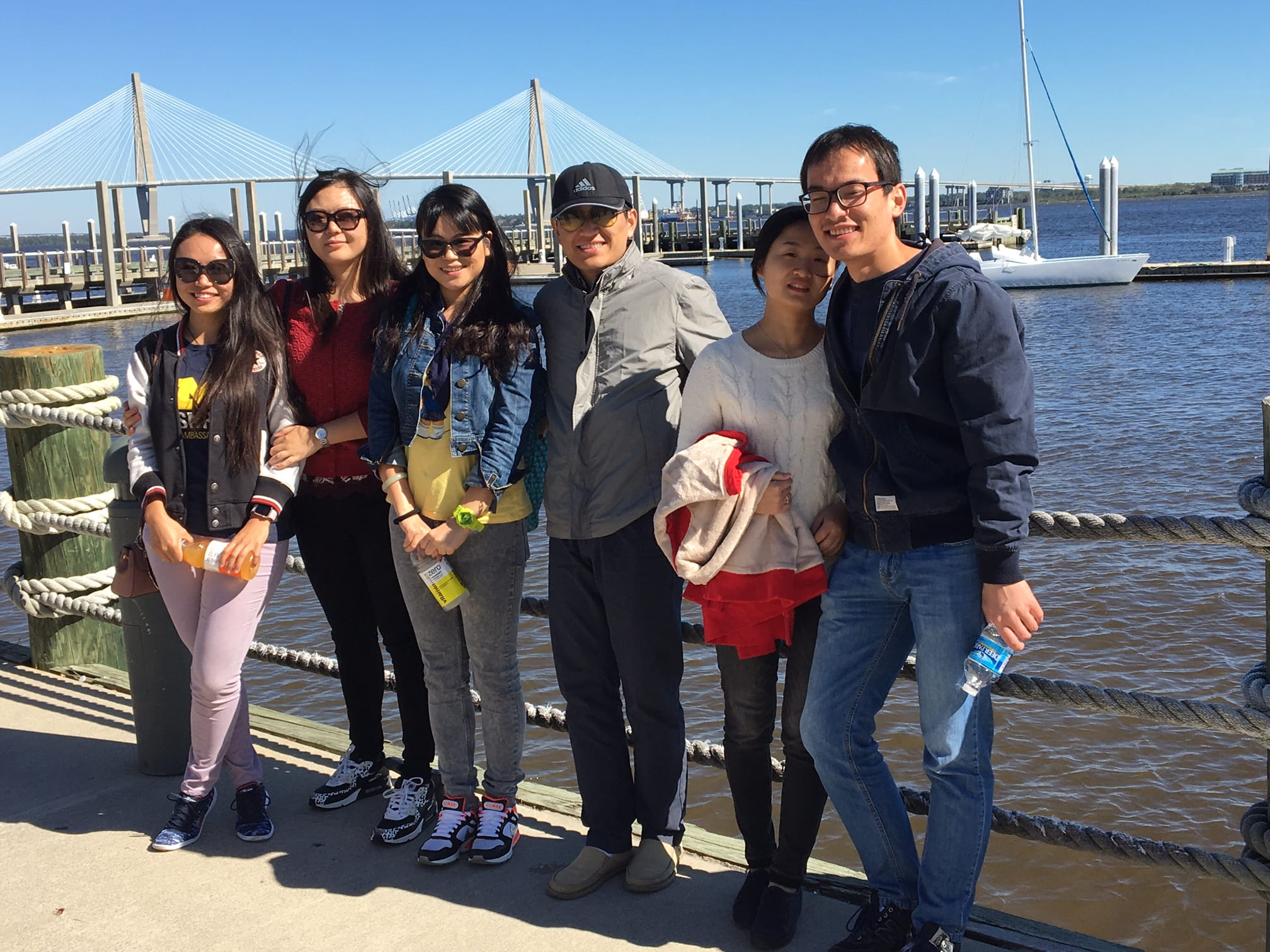 A group of 6 people pose in front of a bridge. 