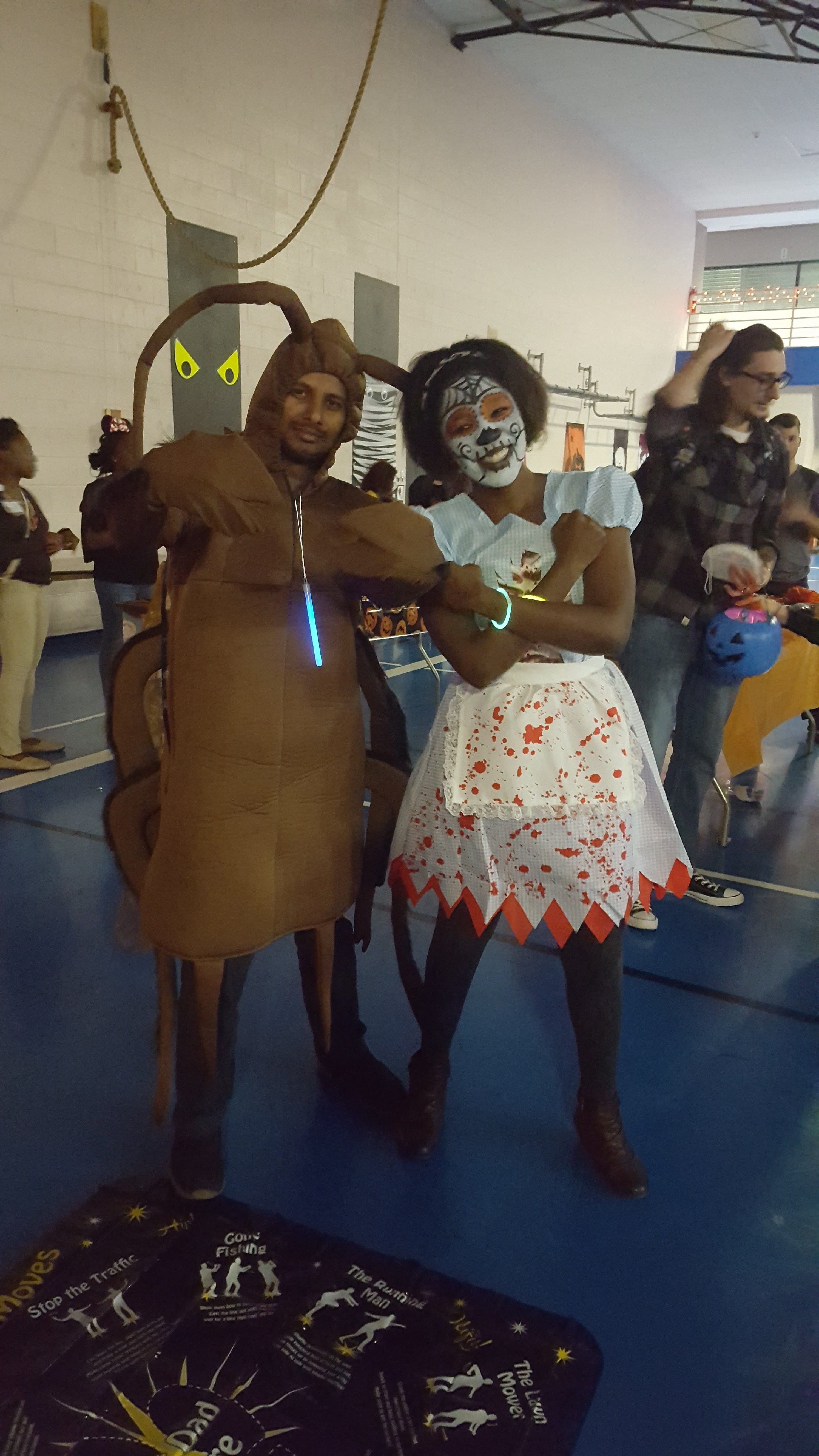 Two volunteers dressed in Halloween costumes give sugar-free candy to children.