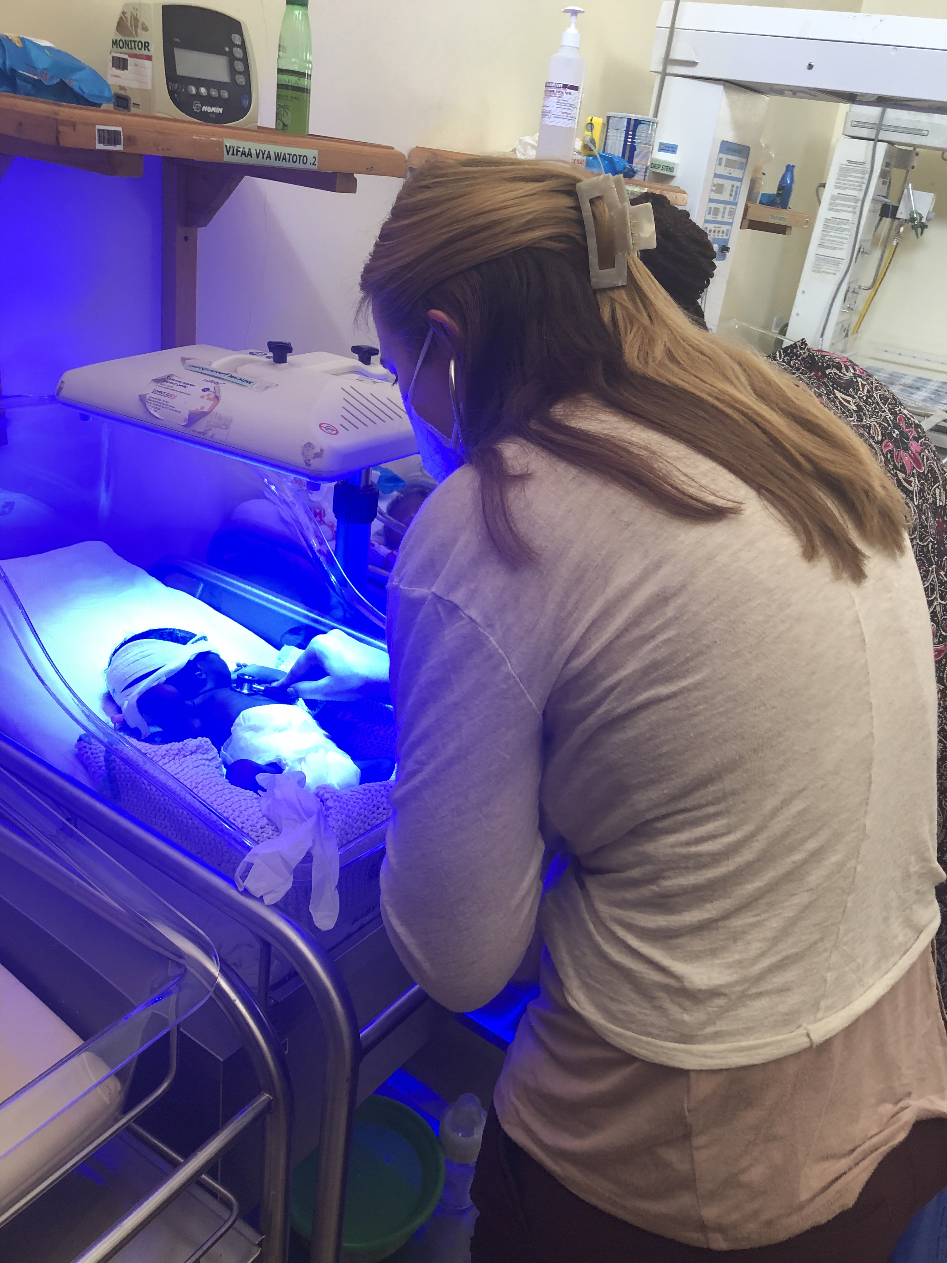 Cassandra Stegall monitors a patient under a light in the NICU.