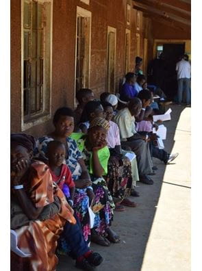 A line of patients wait outside of a clinic.