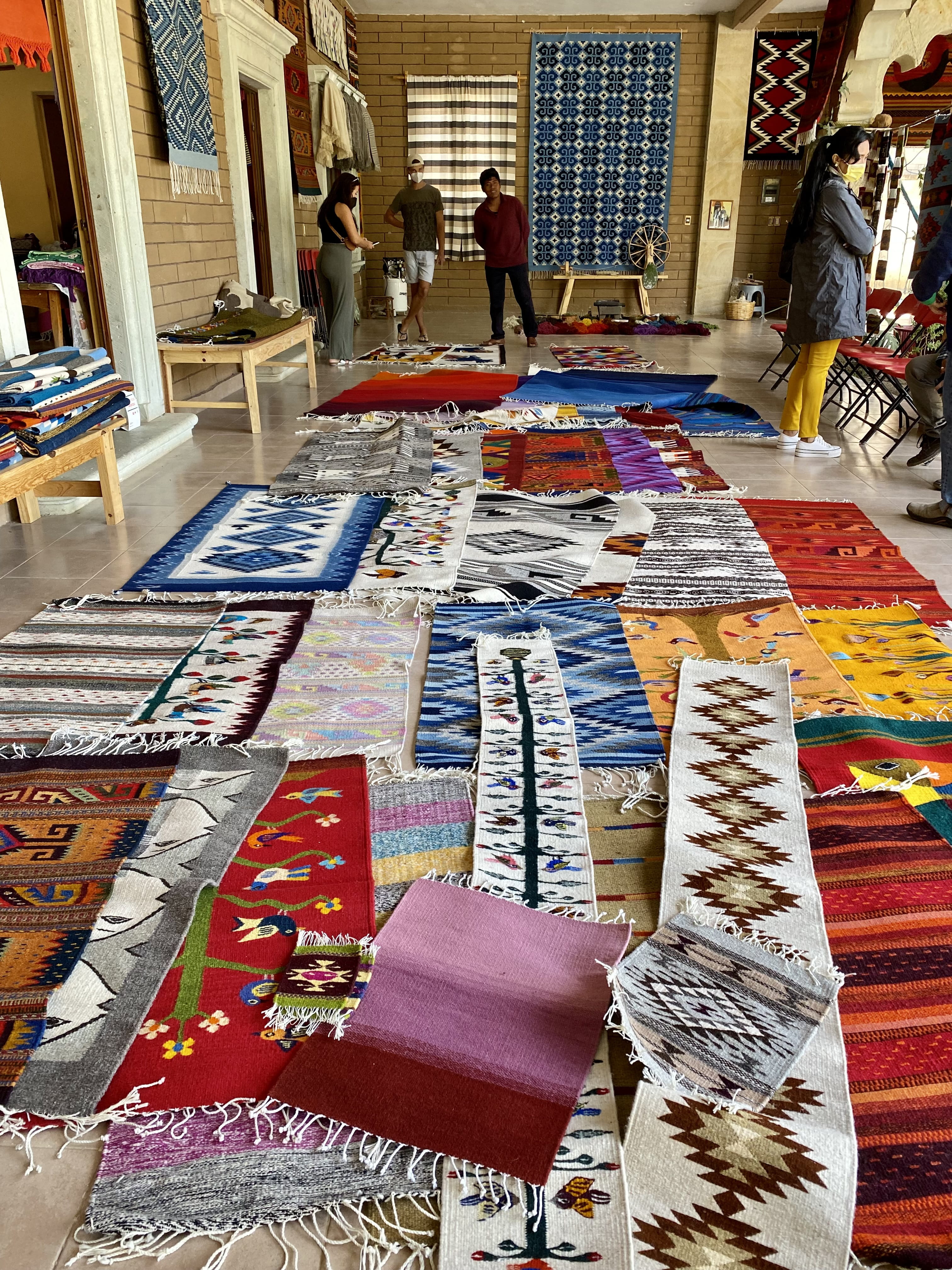 Rug vendor in Oaxaca displaying colorful rugs on floor.