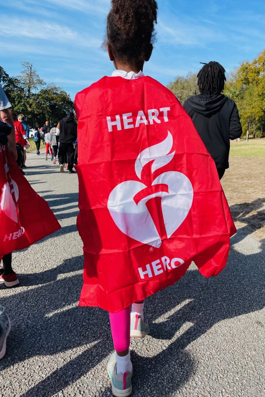 A girl in a American Heart Association banner walks at the event.