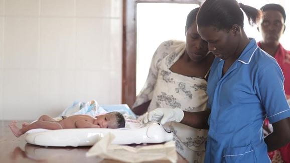 Doctors examine a baby in Uganda