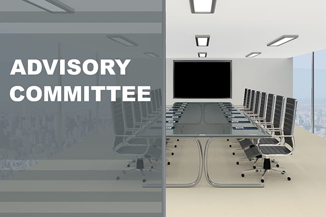 Advisory Committee written in white on gray background overlaid on a boardroom