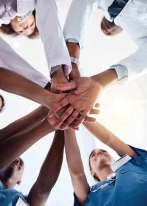 Health care team members standing in a circle putting their hands in