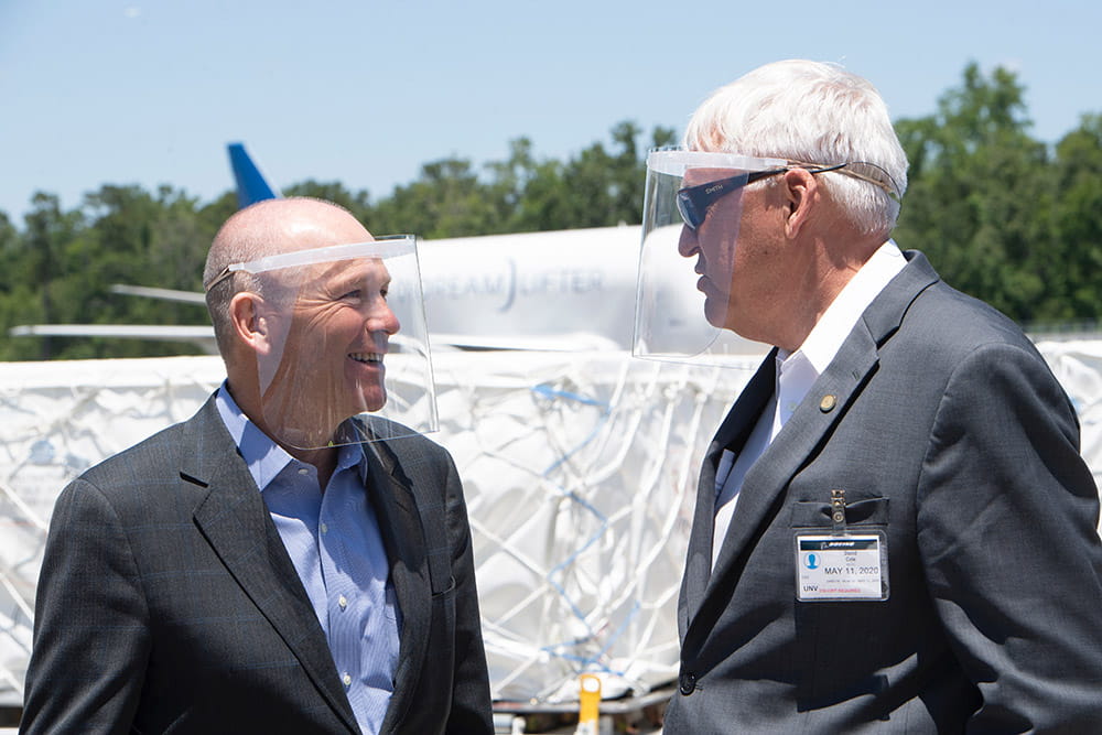 Boeing Global President and CEO Dave Calhoun and David J. Cole, M.D., FACS MUSC president speak to one another while wearing PPE.