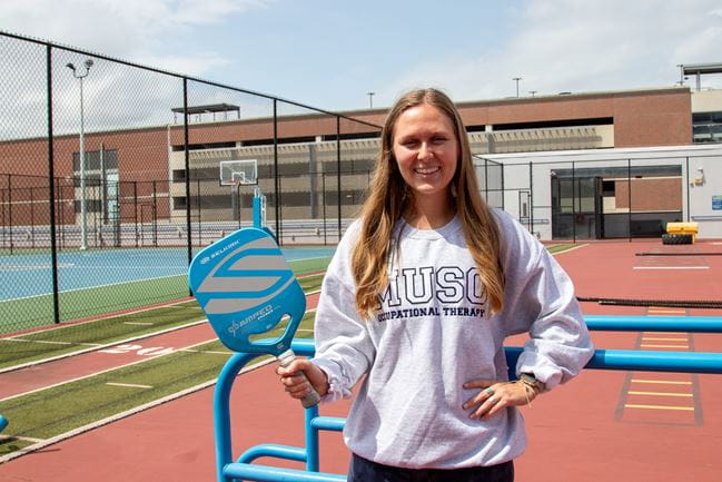 girl standing on rooftop holding pickleball