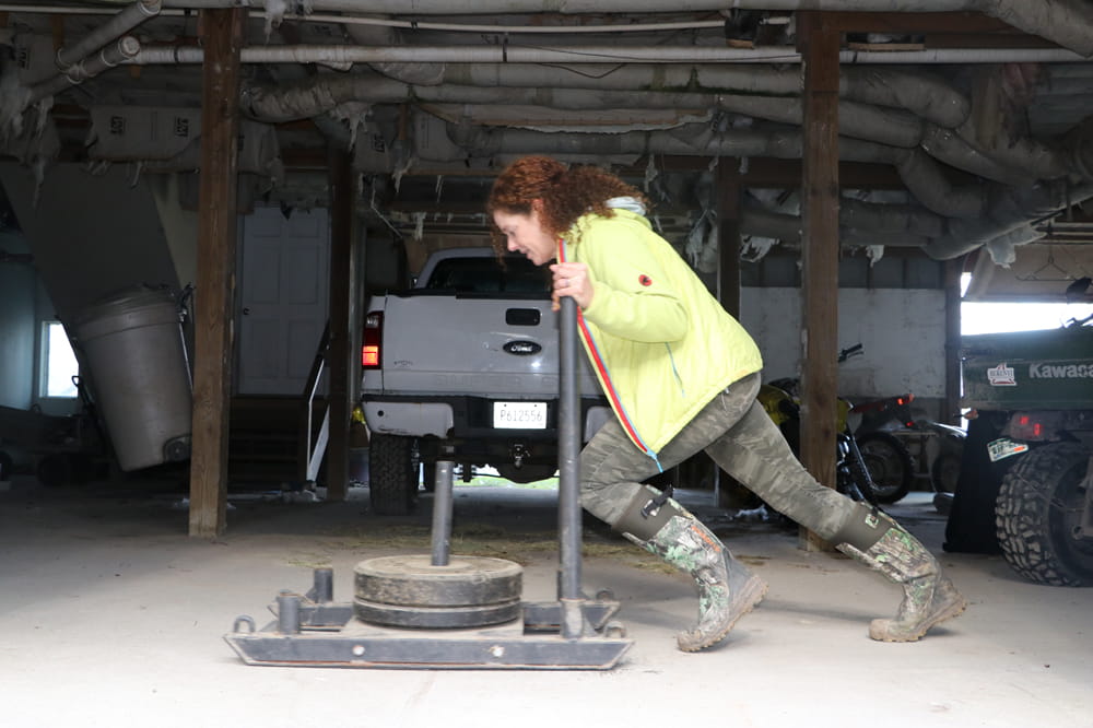 A person pushing a sled during a workout inside of a garage. 