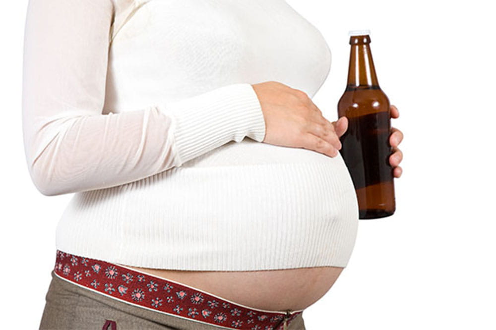 Woman's pregnant belly, beer bottle