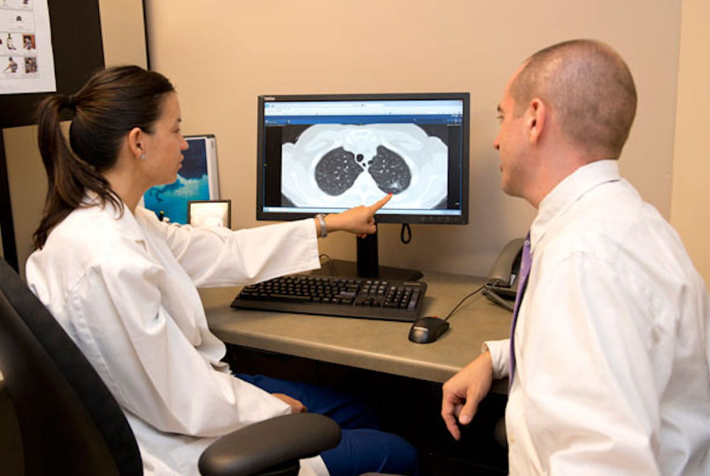 Two researchers at a computer reviewing patient's scan