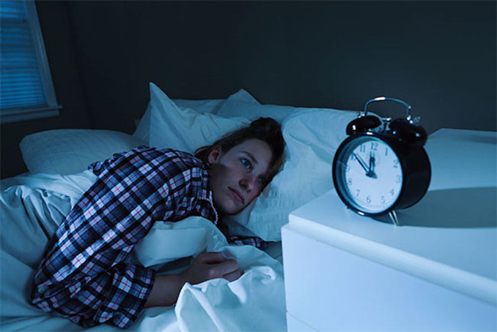 Women in bed with clock on nightstand