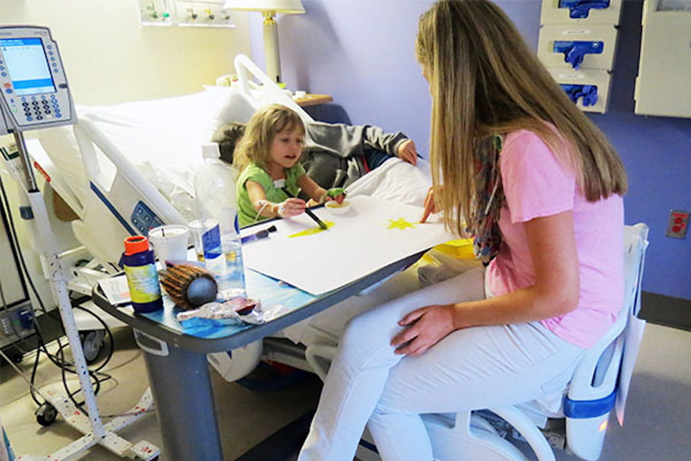 Three-year-old Zoe Collins paints with Child Life specialist Emily Wiebke