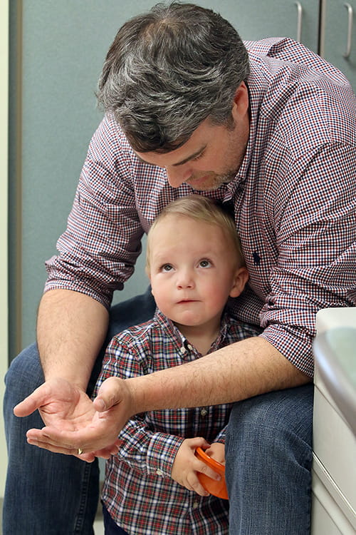 Rhett Bausmith between his father's arms in an exam room. 