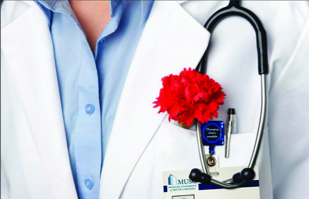 Closeup of doctor's white coat with stethoscope and red carnation in pocket