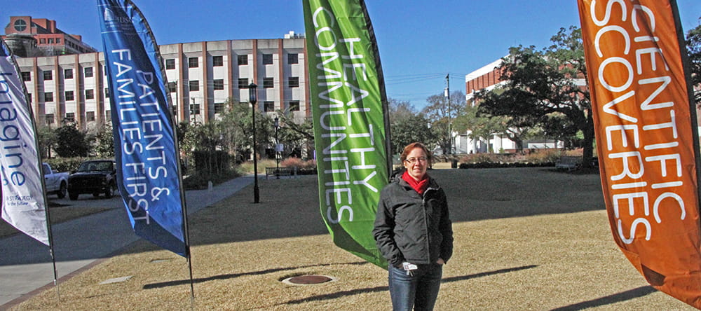 Dr. Heather Boger stands outside by banners proclaiming MUSC's five pillars