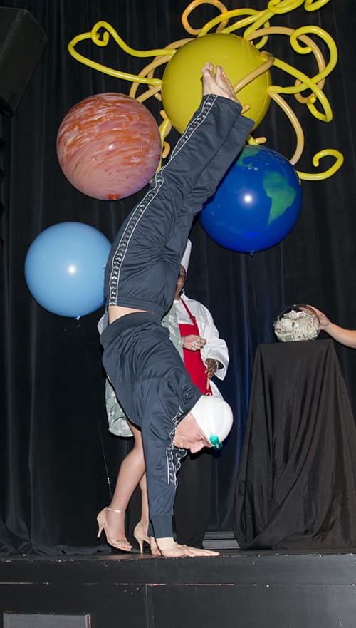 a student walks on his hands across the stage 