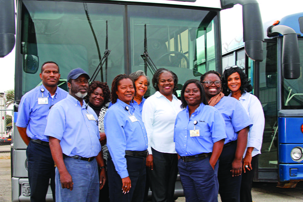 A group of University Transportation employees in front of a shuttle bus