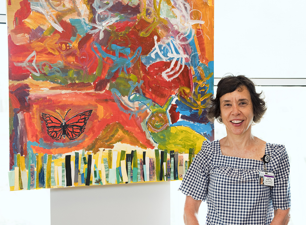 Cynthia Dodds stands in front of a large, vibrant red painting