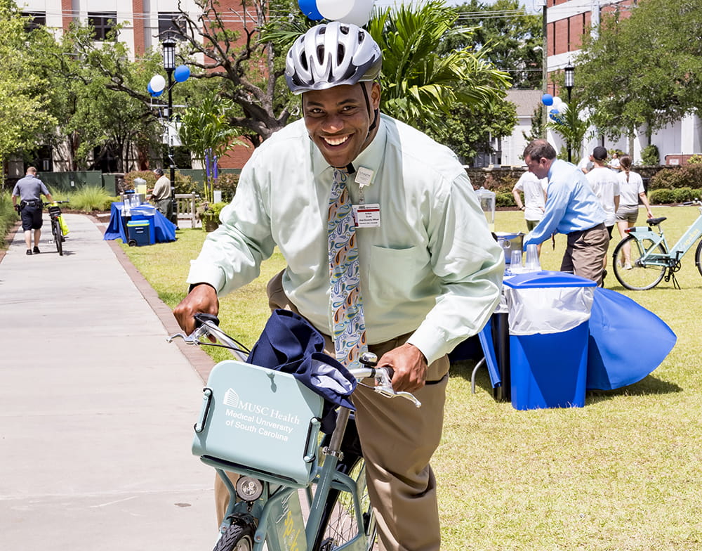 A man in business attire grins as he hops on a bike 