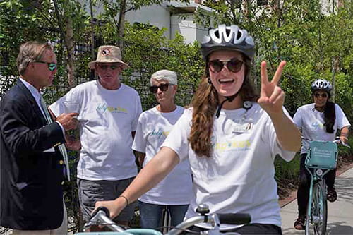 A woman on a bike gives the peace sign 
