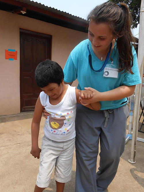 A young woman helps a little boy to walk 