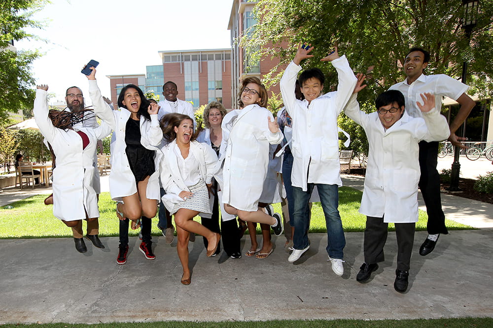 Ann-Marie Broome is surrounded by interns in white lab coats leaping into the air 
