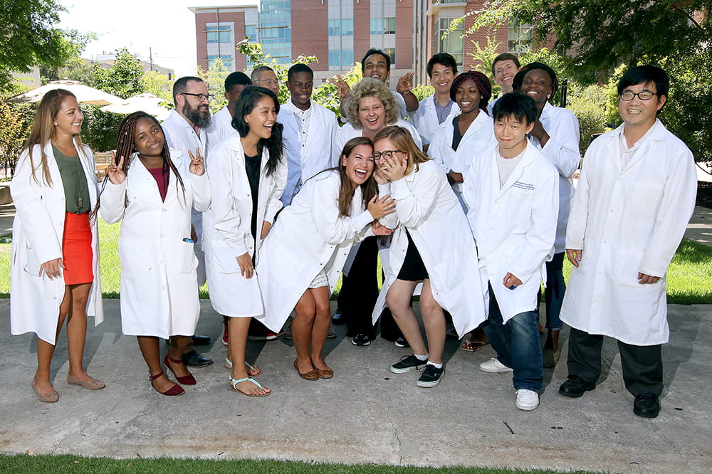 Ann-Marie Broome is surrounded by her summer interns in white lab coats 