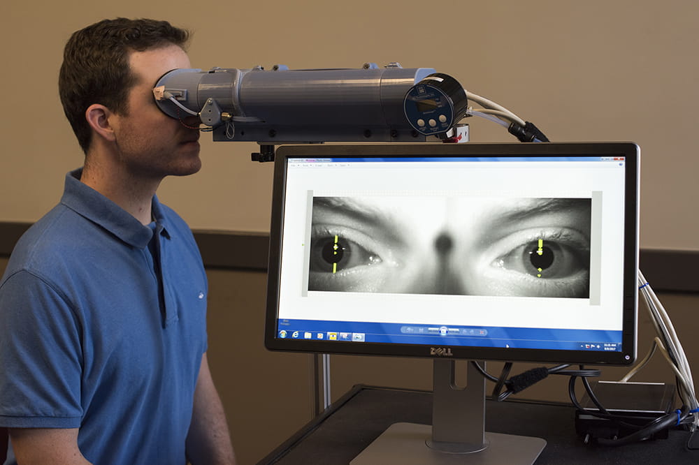 A man looks into a camera device and a large screen shows the image of his eyes