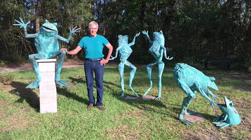 Charles Smith poses with his frog creations