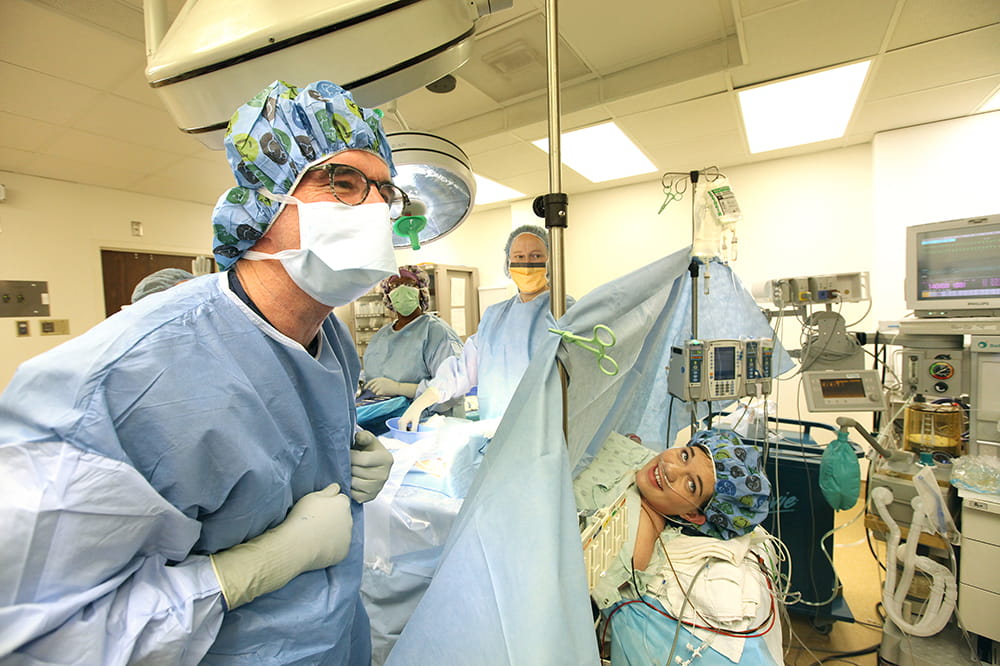 A doctor in scrubs and a woman prepped for a c-section smile as they look at something off camera