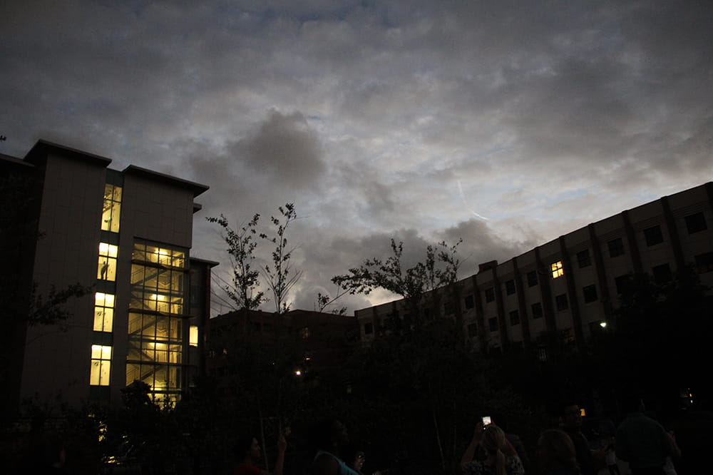 The MUSC campus appears dark and gothic as the buildings are lit from within against a dark and cloudy sky. The blue of the sky is semi-visible behind the clouds