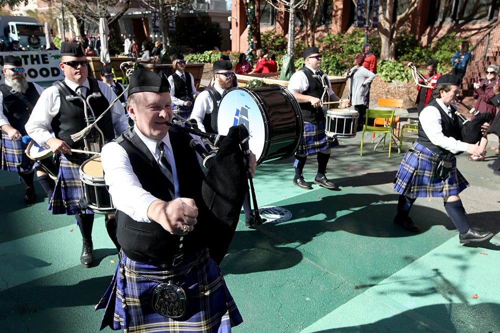 people in kilts playing bagpipes and drums march by