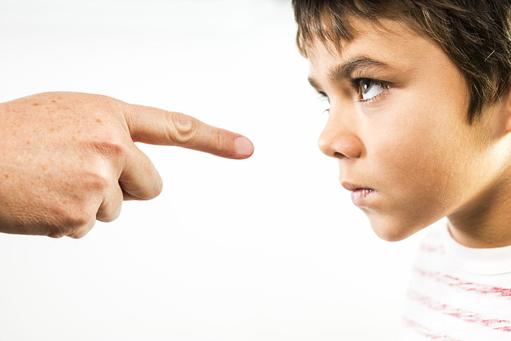 Defiant child with adult finger in his face