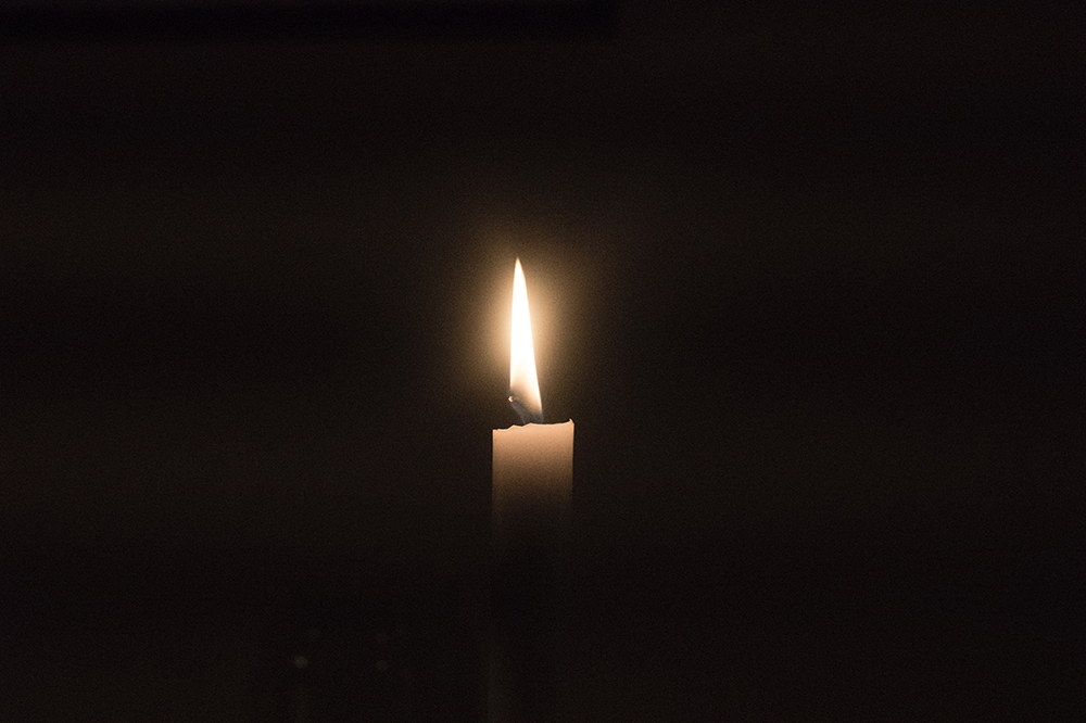 image of a single lit candle in the darkness 