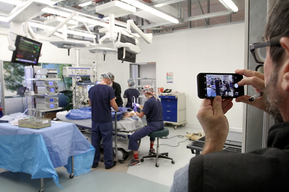 A man uses his phone to record a simulated surgery