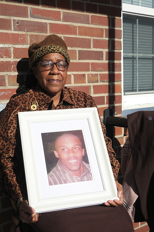 Tyese Miller sits outside her apartment holding a portrait of her son