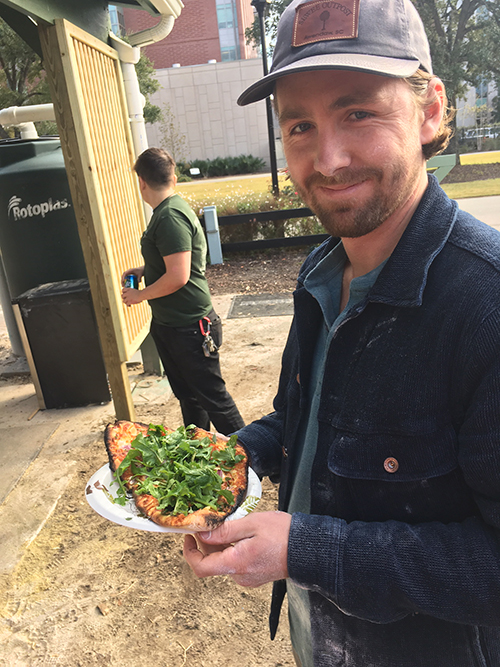 MUSC student George Hanna shows off a pizza cooked in the Urban Farm cob oven