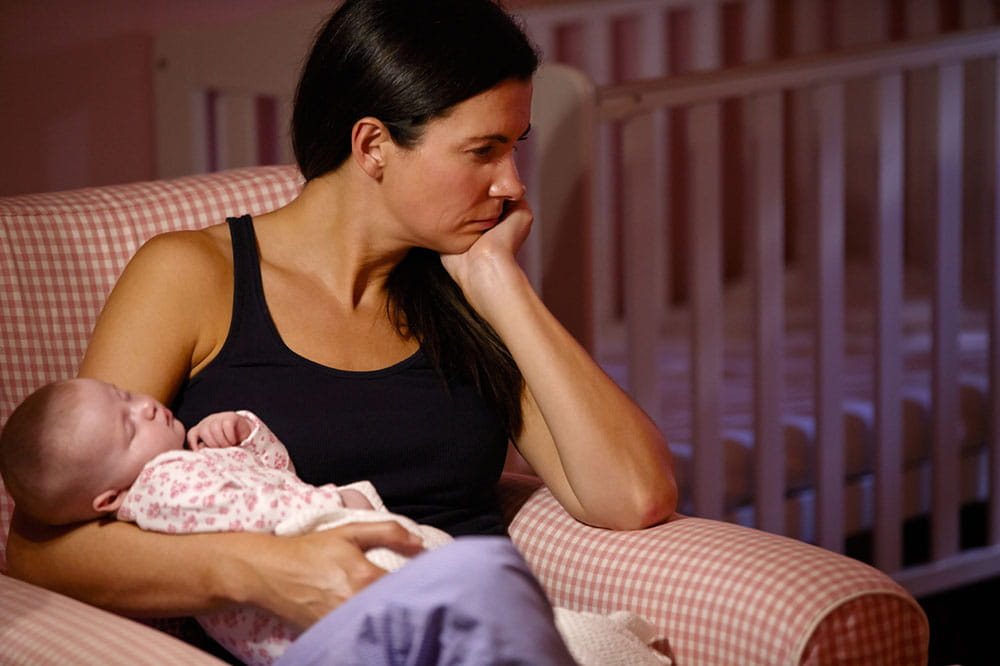 Depressed-looking woman holding a baby