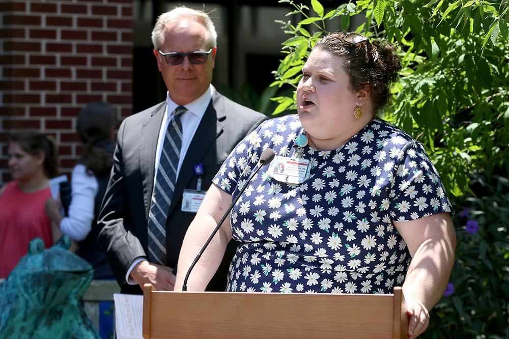 a woman speaks at a podium outside 