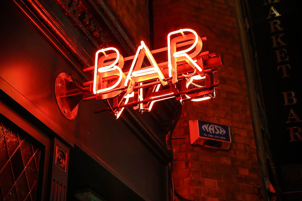 a red neon Bar sign glows in the night 