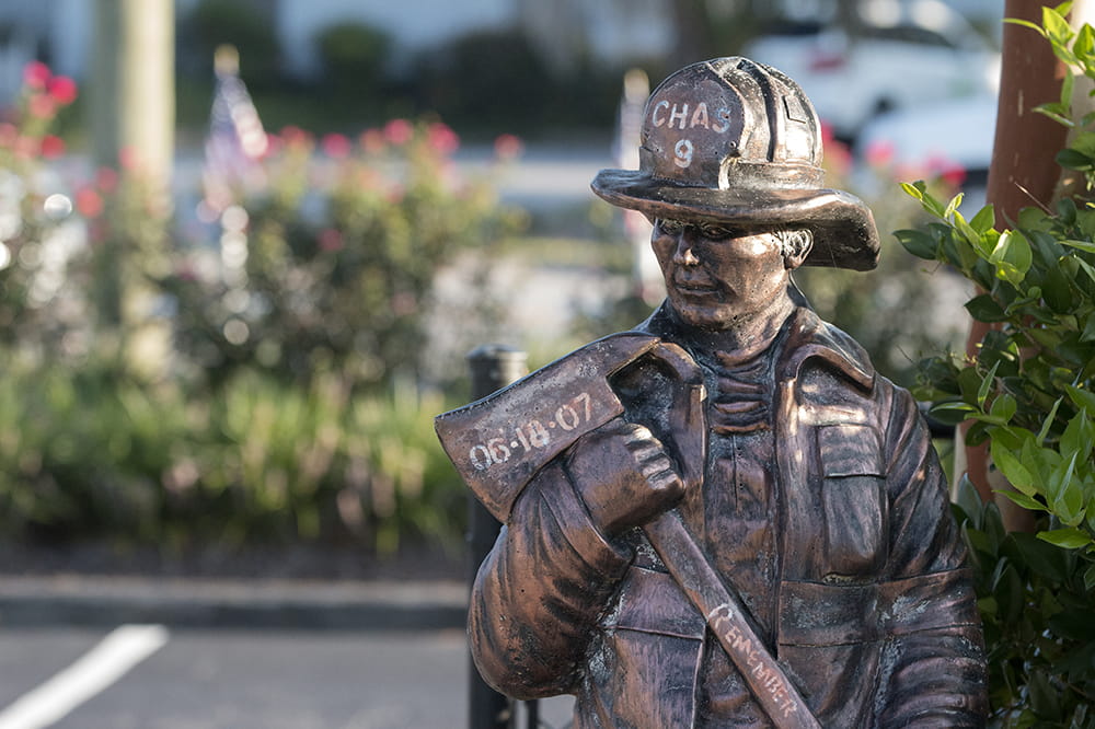 statue of a firefighter holding an ax with the date of 6-18-07, the words Chas 9 and Remember