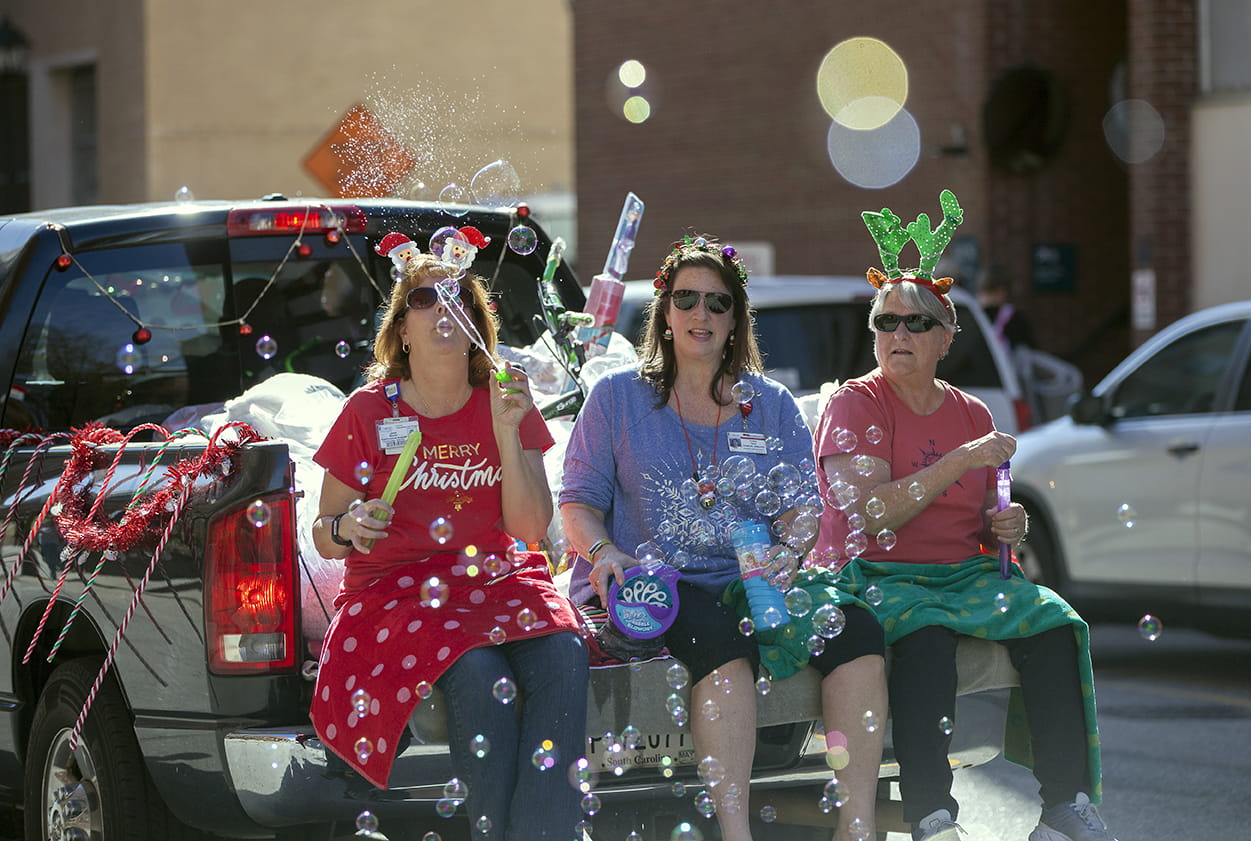 Women blowing bubbles from the back of a truck during the MUSC Angel Tree Parade