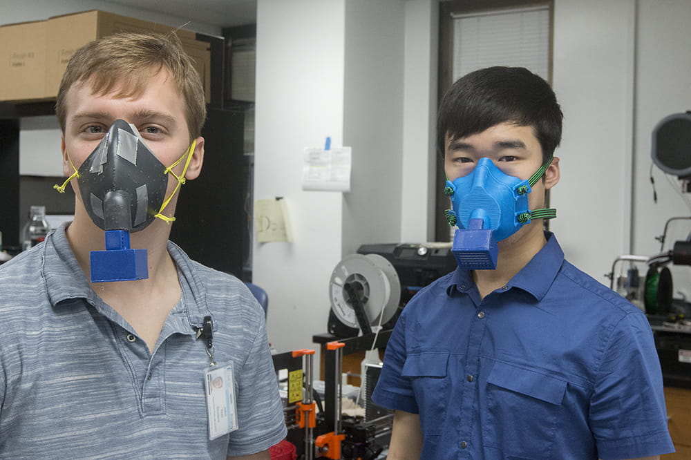 Two men pose with the 3D printed masks 