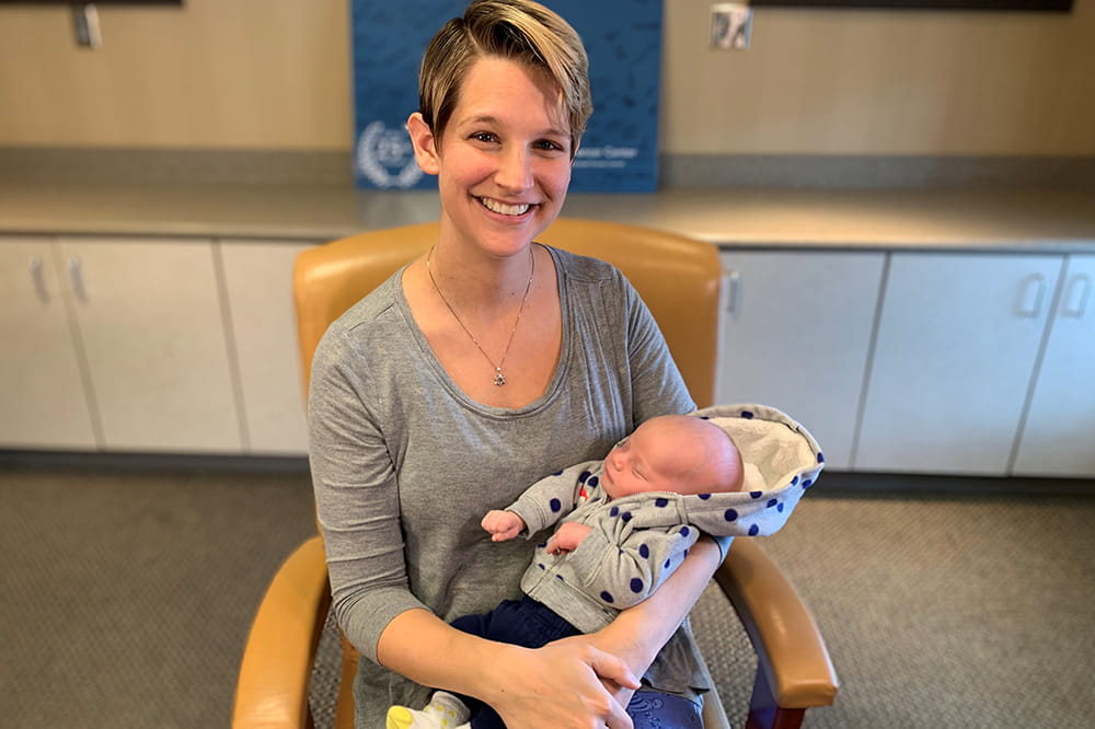 HPV parent ambassador Katie Fox holds her baby in her lap