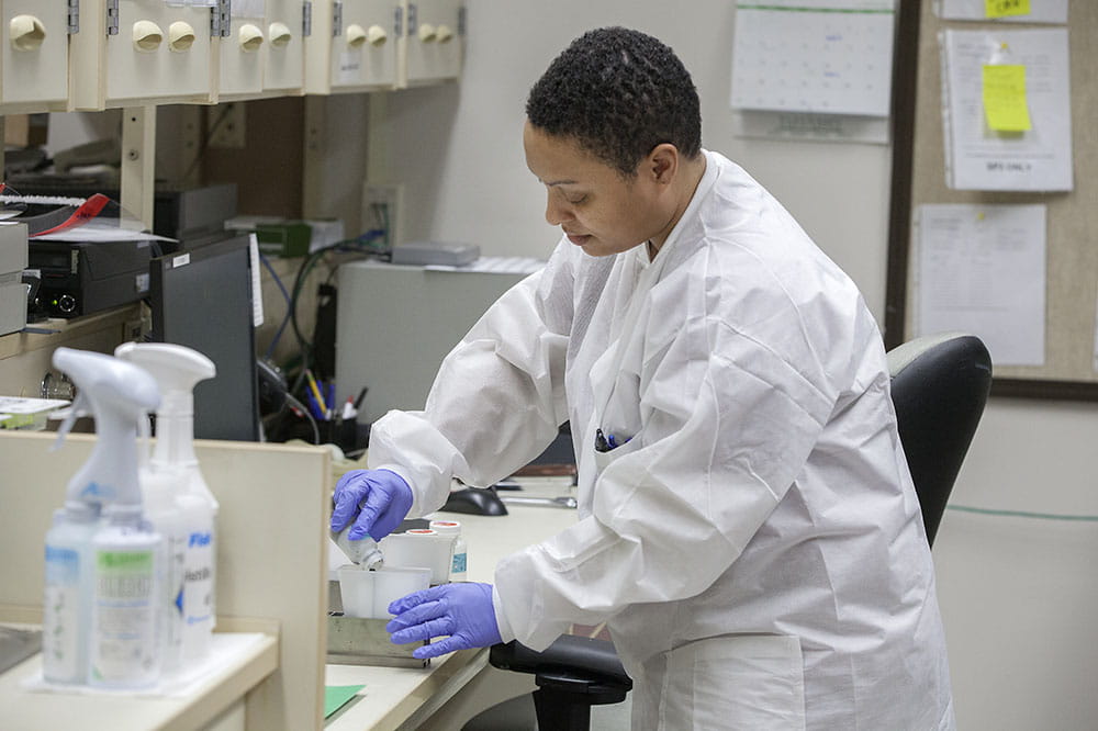 Medical lab technician Tanisha Dickerson puts saline solution into trays to prepare diagnostic instruments for testing.